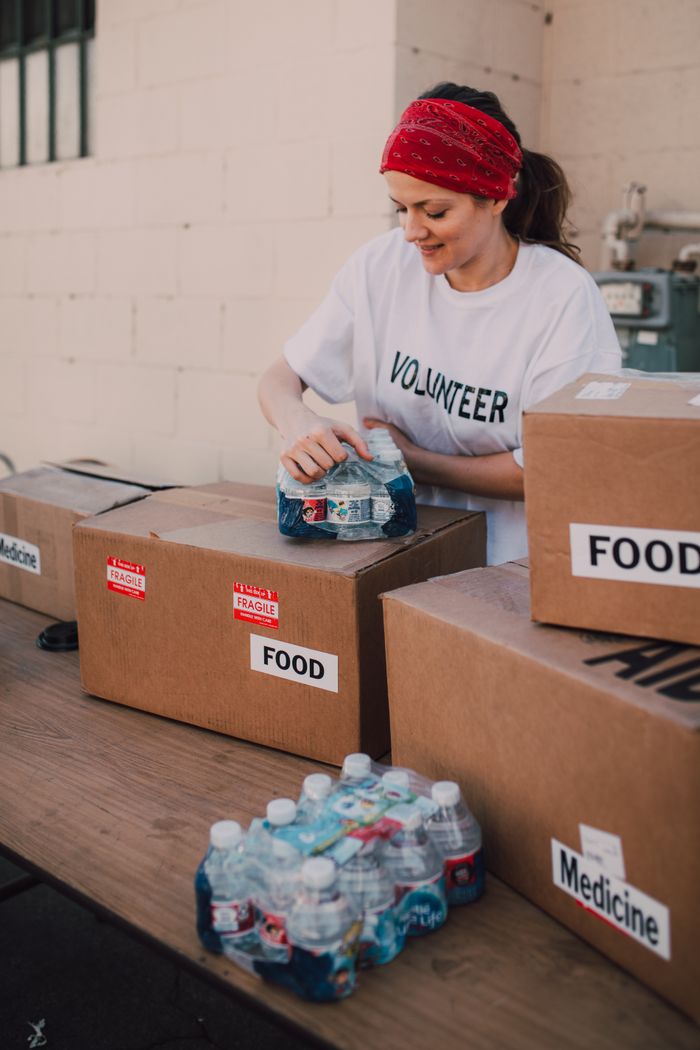 home-services-02 Volunteer packing food and water for charity at an outdoor event, emphasizing community support.